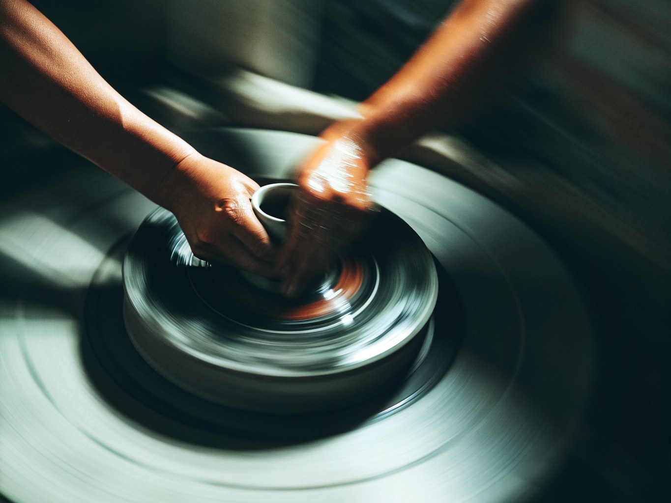 Hands shaping wet clay on a wheel