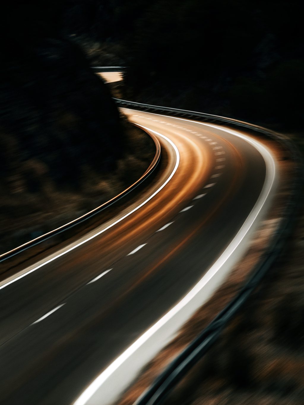 A winding road with light trails at night